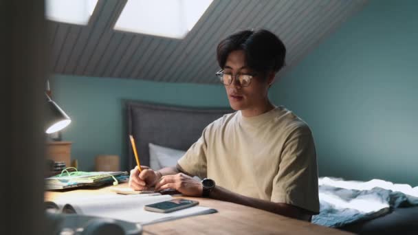 Positive Asian Man Writes His Notepad Talking Phone Home Evening — Video Stock