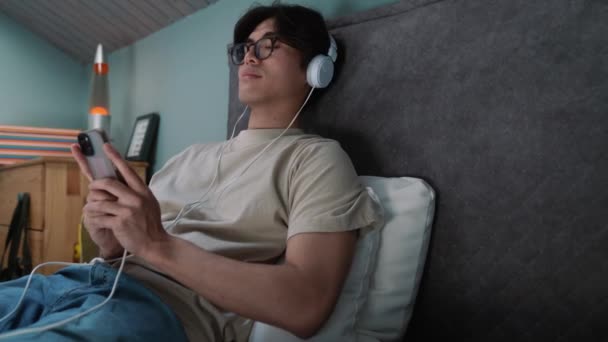 Entspannter Asiatischer Mann Hört Musik Über Kopfhörer Während Hause Auf — Stockvideo