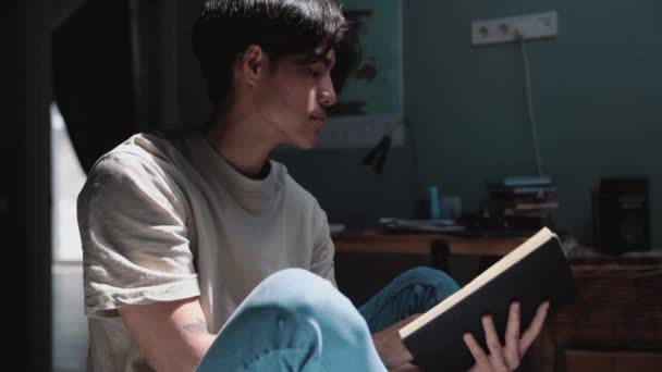 Bonito Asiático Homem Ler Livro Casa — Vídeo de Stock