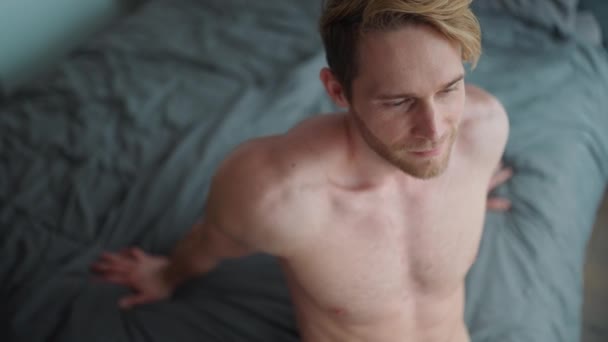 快乐的金发运动员 赤身裸体坐在家里的床上 — 图库视频影像
