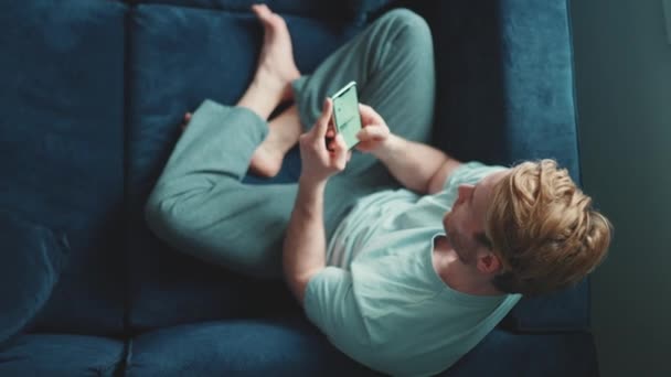 Красивий Блондин Спортивний Чоловік Набирає Мобільний Сидячи Вдома — стокове відео