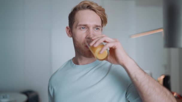 Güzel Sarışın Atletik Adam Evdeki Mutfakta Portakal Suyu Içiyor — Stok video