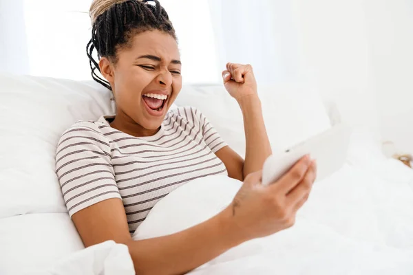 Молода Чорна Жінка Грає Онлайн Гру Мобільному Телефоні Лежачи Вдома — стокове фото