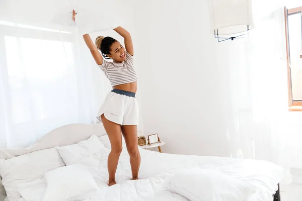 Young Black Woman Laughing While Making Fun Pillow Bed Home — Stok Foto