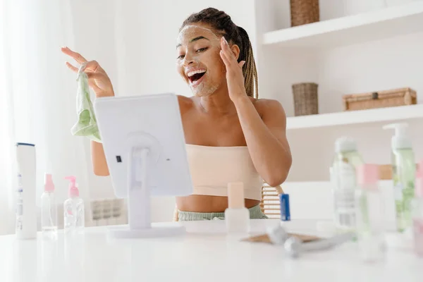 Young Black Woman Cosmetic Mask Smiling Looking Mirror Home — Foto de Stock