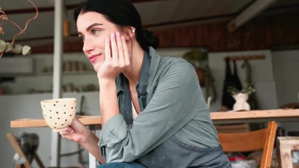 Pensive Morena Oleiro Mulher Beber Chá Após Trabalho Enquanto Sentado — Vídeo de Stock