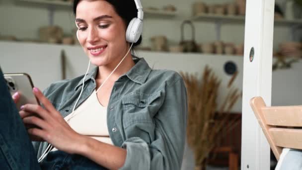 Smiling Brunette Woman Listening Music Headphones Typing Phone While Sitting — 图库视频影像