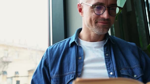 Hombre Concentrado Pelo Gris Leyendo Libro Interior Cafetería — Vídeo de stock