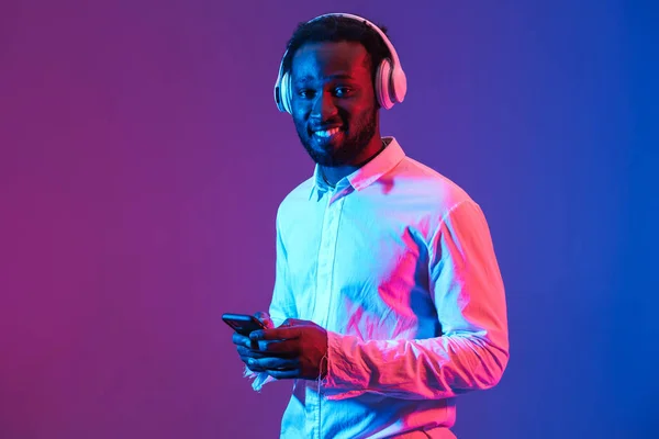 Young Black Man Listening Music Headphones Cellphone Isolated Purple Wall — Stockfoto