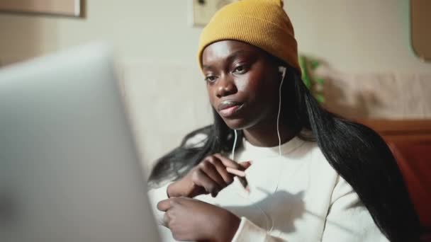 Усміхнена Африканка Білому Светрі Розмовляє Ноутбуку Навушниках Кафе — стокове відео