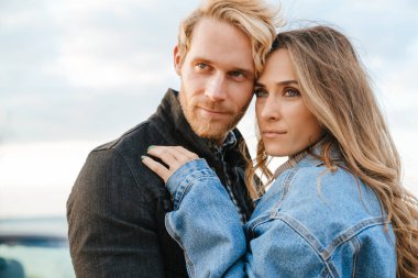 Beyaz, orta yaşlı çift dışarıda yan yana dururken sarılıyorlar.