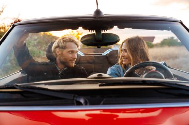 Yolculuk sırasında araba sürerken birlikte gülümseyen beyaz çift.