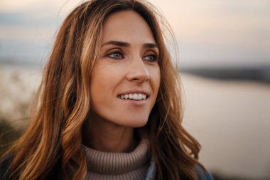 Beyaz kızıl kadın gülümsüyor ve dışarı bakıyor.