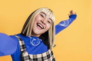 Kopyalama alanı gösteren Asyalı kız sarı duvarda izole edilmiş selfie çekiyordu.