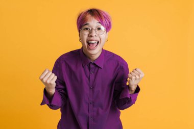 Gözlüklü Asyalı çocuk sarı duvarın üzerinde inzivaya çekilmiş jest ve çığlıklar atıyor.