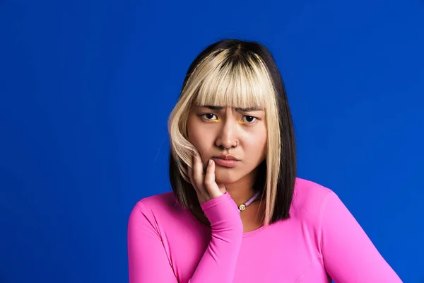 Asian Girl Piercing Frowning Looking Camera Isolated Blue Wall — Stockfoto