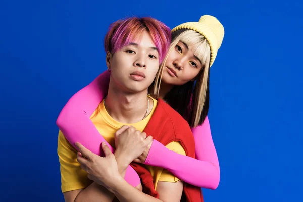 Asian Couple Multicolored Hair Hugging Looking Camera Isolated Blue Wall — Stockfoto