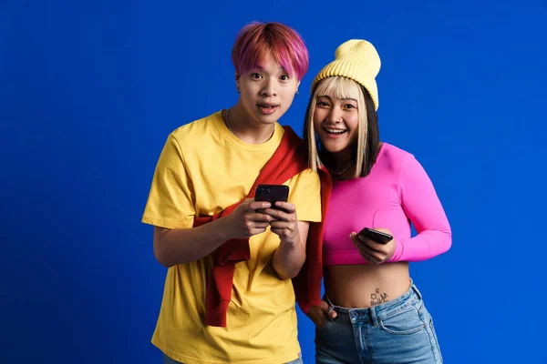Asian Teenagers Multicolored Hair Smiling While Using Cellphones Isolated Blue — Fotografia de Stock