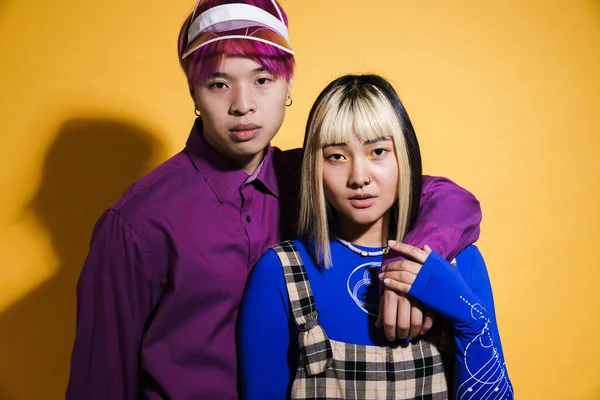 Sarılıp poz veren Asyalı çift sarı duvarın üzerinde izole edilmiş.