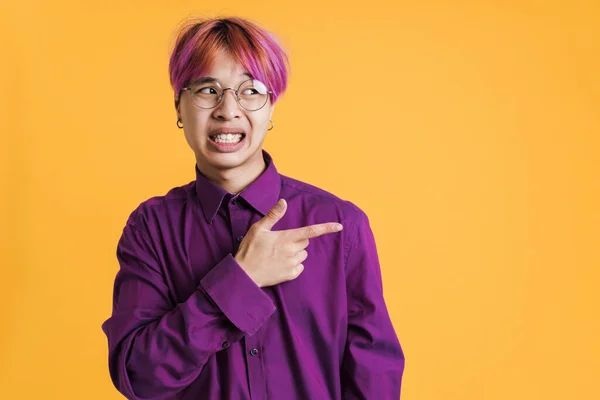 Asian Displeased Boy Grimacing Pointing Finger Aside Isolated Yellow Wall — Zdjęcie stockowe