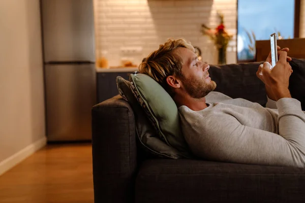 Ingwerborsten Mann Benutzt Handy Während Hause Auf Sofa Liegt — Stockfoto