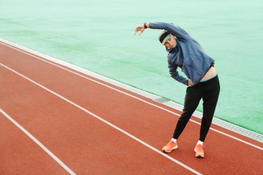 Genç beyaz koşucu dışarıda çalışırken egzersiz yapıyor.