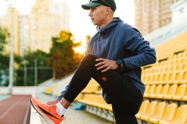 Genç sporcu dışarıda stadyumda çalışırken egzersiz yapıyor.