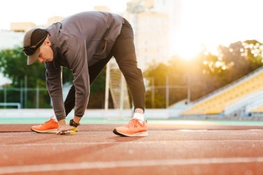 Genç sporcu dışarıda stadyumda çalışırken egzersiz yapıyor.