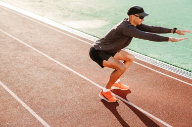 Genç beyaz koşucu dışarıda stadyumda çalışırken egzersiz yapıyor.