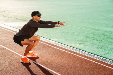 Genç beyaz koşucu dışarıda stadyumda çalışırken egzersiz yapıyor.