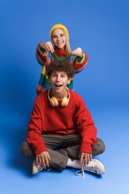 Beyaz kız ve erkek birlikte eğlenirken gülüyor mavi arka planda.