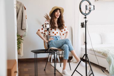 Beyaz kadın evde cep telefonuyla selfie çekerken gülüyor.