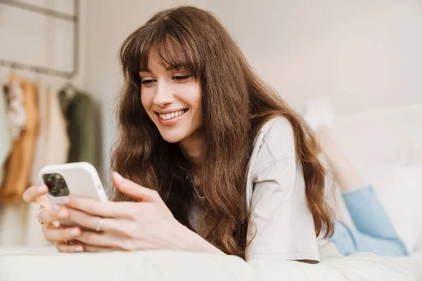 White Woman Smiling Using Mobile Phone While Lying Bed Home — Stockfoto