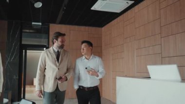 Concentrated multinational colleagues talking about work while walking in the office