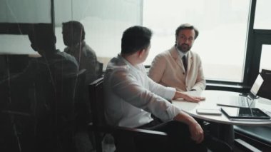 Two serious multinational colleagues talking about work in the office