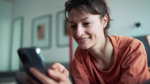 Cheerful Brunette Woman Texting Phone While Lying Bed Home — Vídeo de Stock