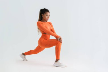 Siyahi genç sporcu kadın beyaz arka planda izole bir şekilde çalışırken egzersiz yapıyor.