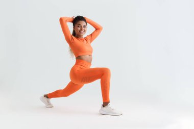 Black young sportswoman doing exercise while working out isolated over white background