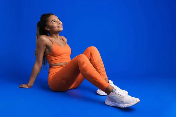 Black Young Sportswoman Smiling While Sitting Floor Isolated Blue Background — Stockfoto