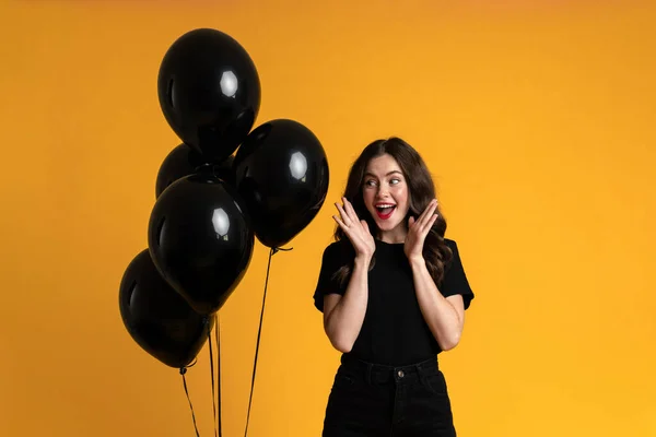 White Woman Expressing Surprise While Posing Black Balloons Isolated Yellow — 图库照片