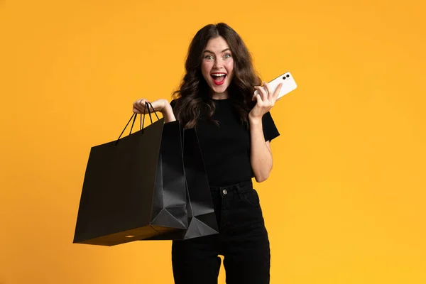 White Excited Woman Posing Shopping Bags Cellphone Isolated Yellow Background — Stock fotografie