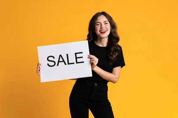 White Young Woman Smiling While Posing Sale Placard Isolated Yellow — стоковое фото