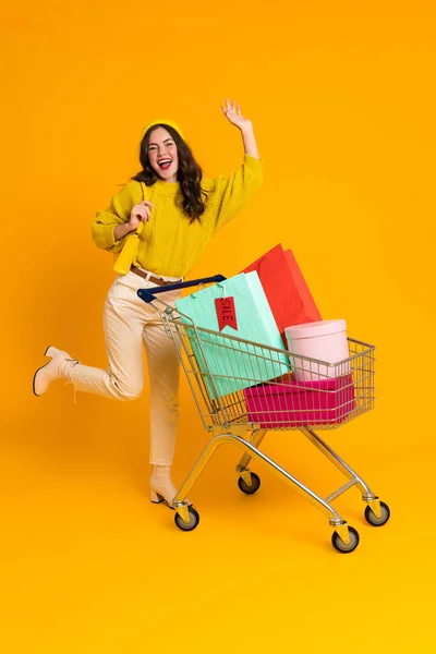 White Woman Making Fun While Posing Shopping Cart Isolated Yellow — Φωτογραφία Αρχείου