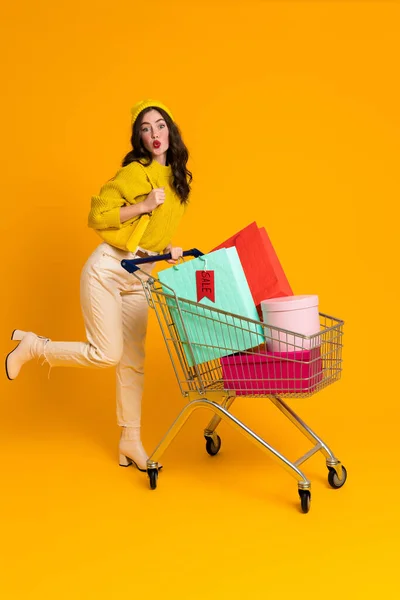 White Excited Woman Grimacing While Posing Shopping Cart Isolated Yellow — Foto de Stock