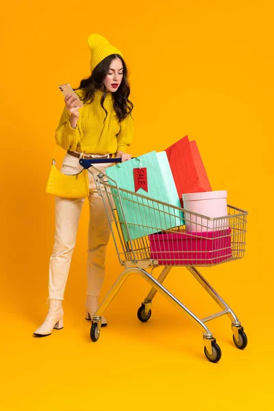 White Young Woman Posing Cellphone Shopping Cart Isolated Yellow Background — Photo
