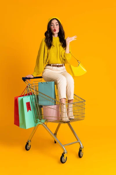 White Woman Grimacing While Sitting Shopping Cart Isolated Yellow Background — Photo