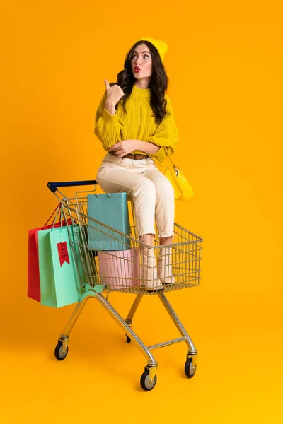 White Woman Pointing Finger Aside While Sitting Shopping Cart Isolated — Photo