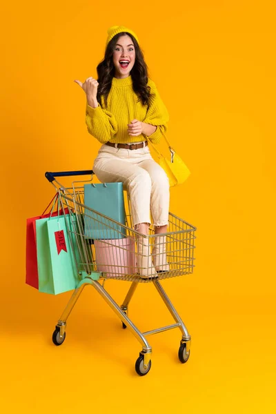 White Woman Pointing Finger Aside While Sitting Shopping Cart Isolated — Foto de Stock
