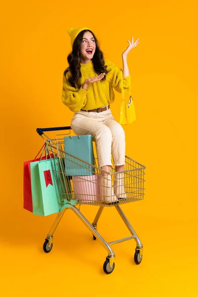 White Woman Holding Copyspace While Sitting Shopping Cart Isolated Yellow — Photo