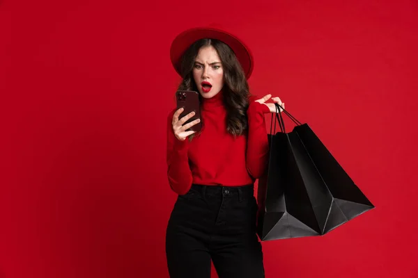 White Woman Using Cellphone While Posing Shopping Bags Isolated Red — Stock fotografie